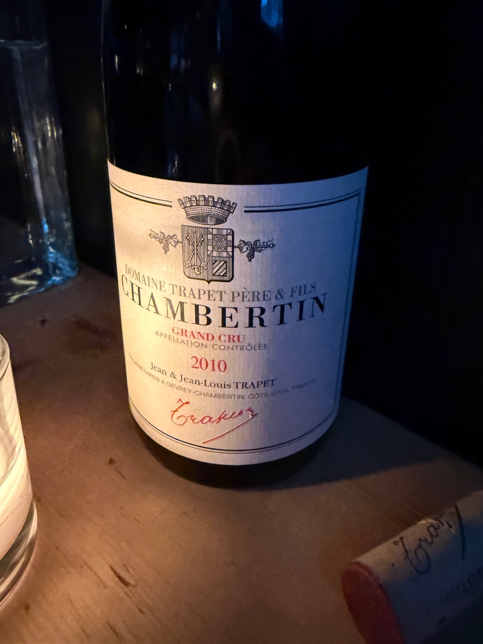 A bottle of 2010 Domaine Trapet Chambertin Grand Cru on a dinner table