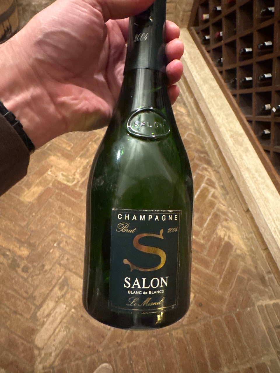 A bottle of 2004 Salon Le Mesnil Blanc de Blancs held in a wine cellar